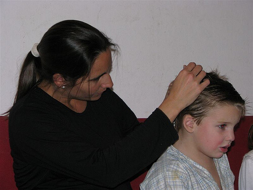 Mamă curățând părul copilului de păduchi