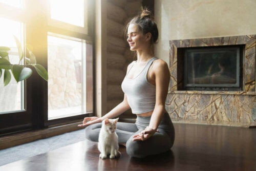 Femeie practicând meditație împreună cu pisica sa