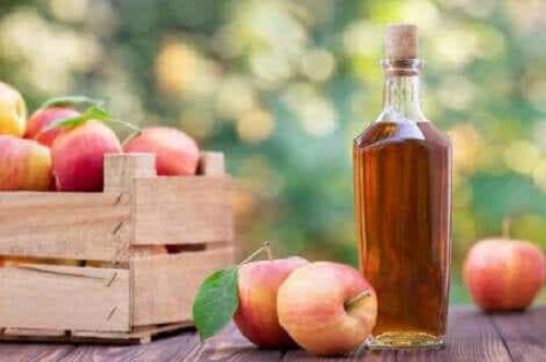 Sticlă cu oțet lângă o ladă cu mere