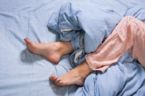 Femeie care suferă de sindromul picioarelor neliniștite