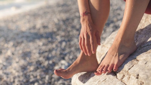 Femeie cu picioarele goale pe plajă