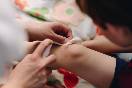 Asistent medical dezinfectând rana unui tânăr