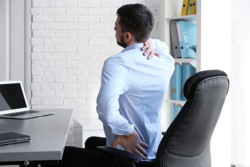 Bărbat adoptând obiceiuri care ameliorează durerea lombară la birou