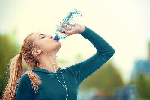 Femeie consumând o băutură pentru sportivi în timp ce face jogging