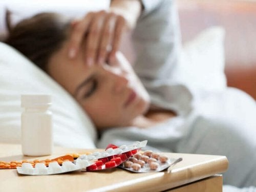 Femeie bolnavă cu medicamente pe noptieră