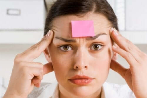 Femeie cu hârtie lipită de frunte experimentând simptomele amneziei