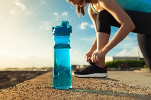 Sportivă antrenându-se cu o sticlă de apă