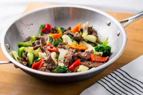 Gospodină ilustrând cum se prepară bibimbap în tigaie wok