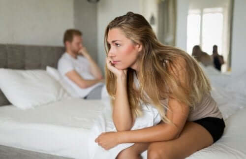 Barbat și femeie stând în pat și care se ignoră