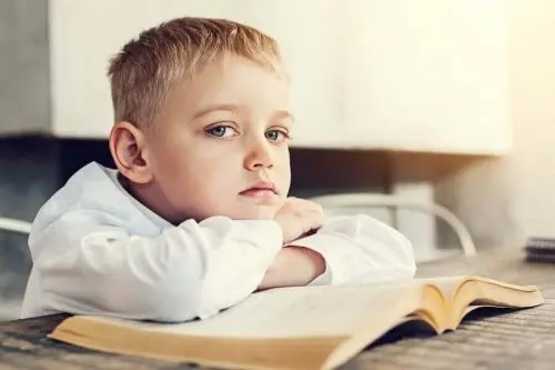 Copil care stă cu capul pe o carte