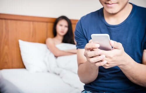 Femeie privindu-și iubitul cum își butonează telefonul mobil