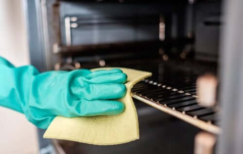 Mână curățând interiorul unui cuptor cu o cârpă