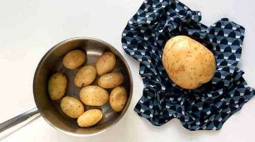 Oală cu cartofi mici lângă un cartof mare