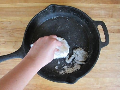 Persoană curățând o tigaie cu un detergent natural