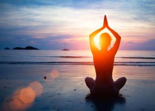Persoană practicând yoga pe plajă pentru a avea o sănătate mintală optimă