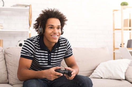 Băiat stând pe canapea și jucându-se un joc video pe consolă