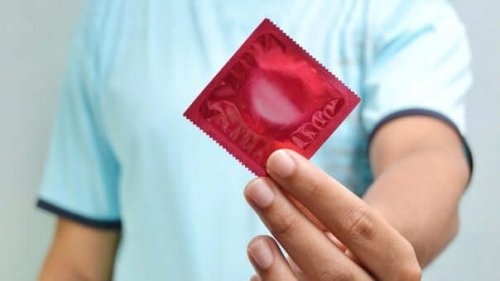 Bărbat care ține în mână un prezervativ