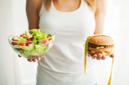 Femeie ținând în mână alimente pentru prevenirea obezității și un burger