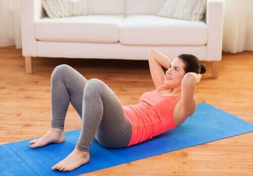 Femeie antrenându-și mușchii abdominali acasă