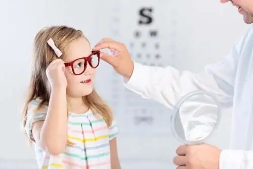 Medic care îi pune ochelari unei fetițe