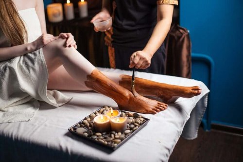 Specialist aplicând argilă pe picioarele unei cliente
