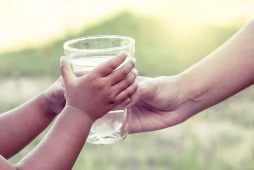 Copil care primește un pahar cu apă