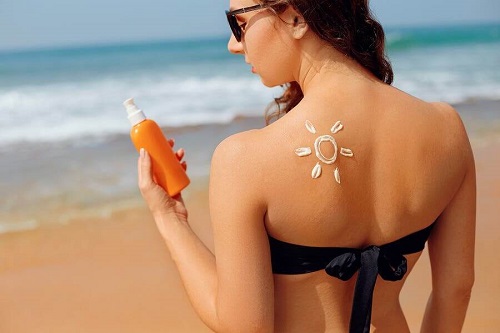 Femeie la plajă aplicând cremă de protecție solară