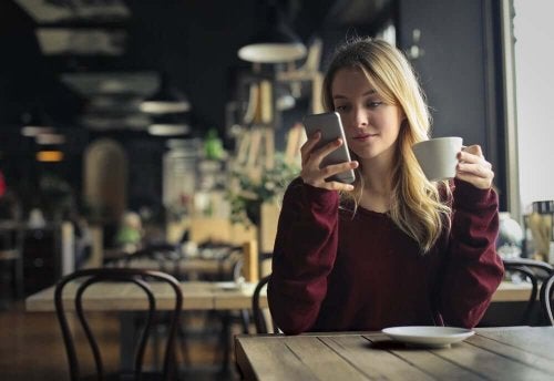 Femeie verificându-și telefonul mobil la cafenea
