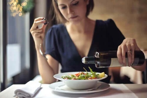 Femeie care toarnă ulei peste salată