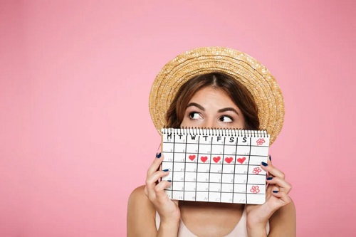 Fată care ține în mână un calendar menstrual