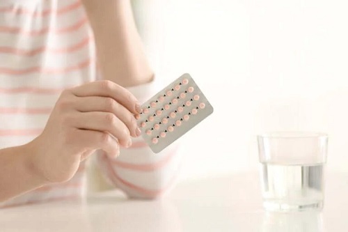 Femeie care ține în mână o folie de pilule anticoncepționale