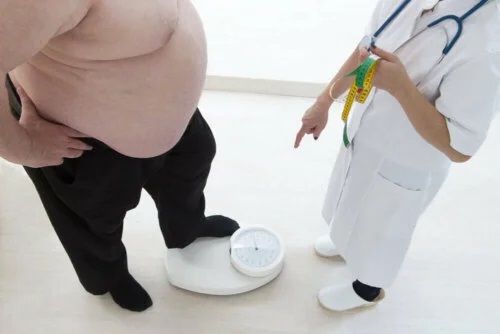 Medic care urcă un pacient obez pe cântar