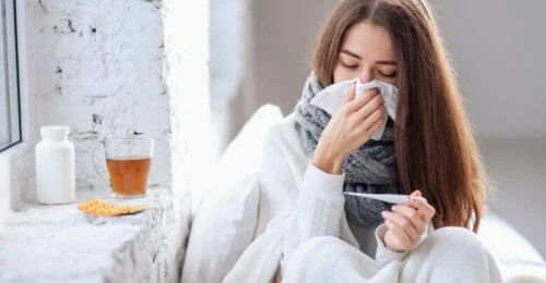 Femeie răcită care își suflă nasul