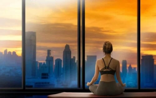 Femeie care face yoga în fața geamului