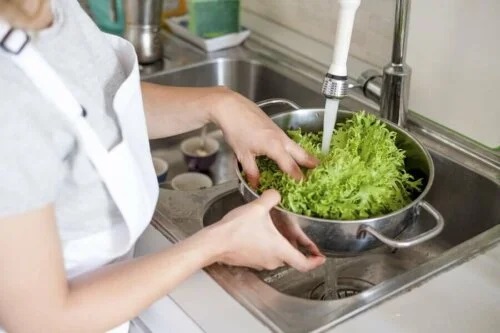 Femeie care spală o salată în chiuvetă