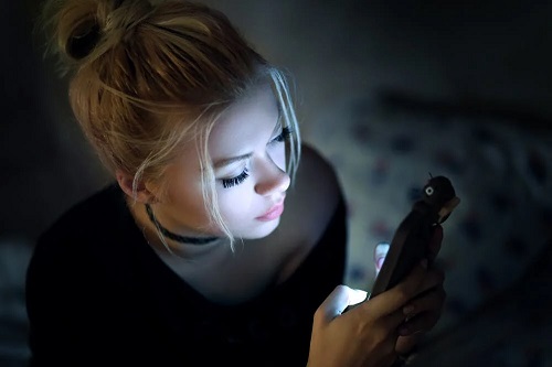 Tânără care butonează telefonul noaptea