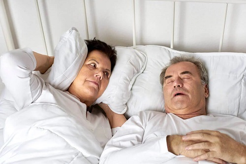 Bărbat care sforăie și își deranjează partenera