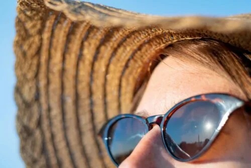 Femeie la plajă cu pălărie și ochelari de soare