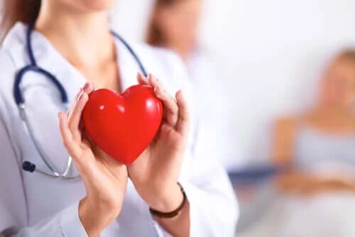 Medic care ține în mână o inimă roșie
