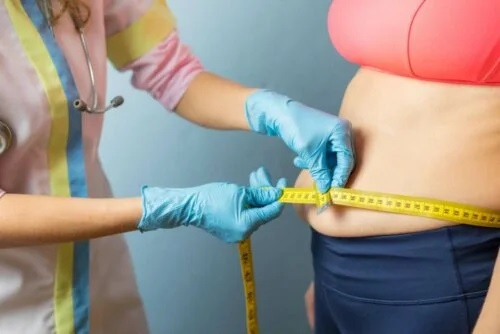Medic care măsoară talia unei paciente obeze