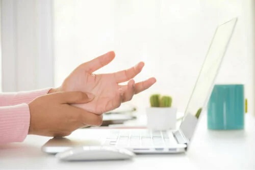 Persoană cu mâinile amorțite la laptop