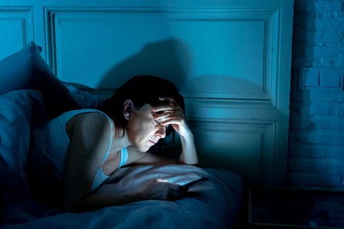 Femeie care butonează telefonul noaptea