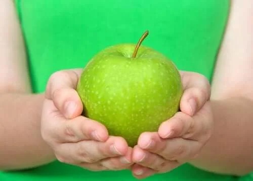 Persoană care ține un măr verde