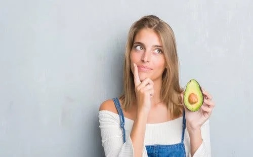 Femeie care ține în mână un avocado