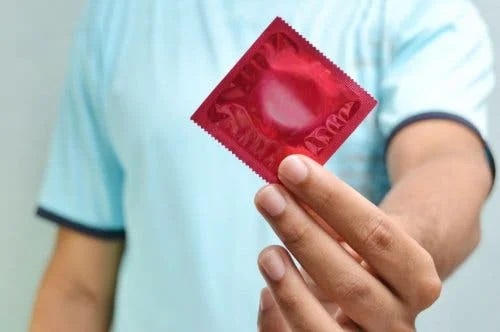 Bărbat care ține un prezervativ