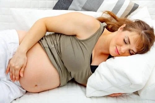 Femeie gravidă întinsă în pat