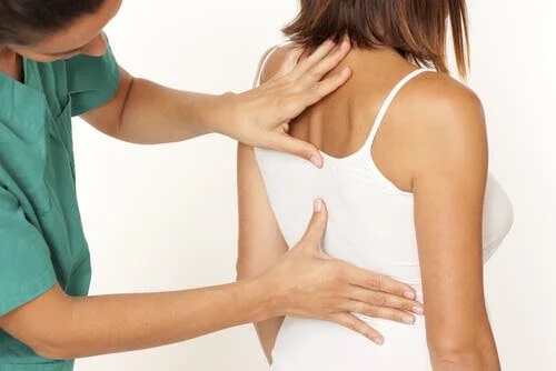 Medic care examinează spatele unui pacient