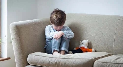 Copil trist stând e canapea