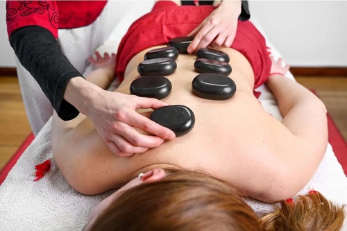 Terapeut care practică masajul cu pietre fierbinți