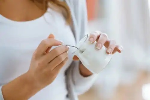 Femeie care consumă iaurt și fructe la cină